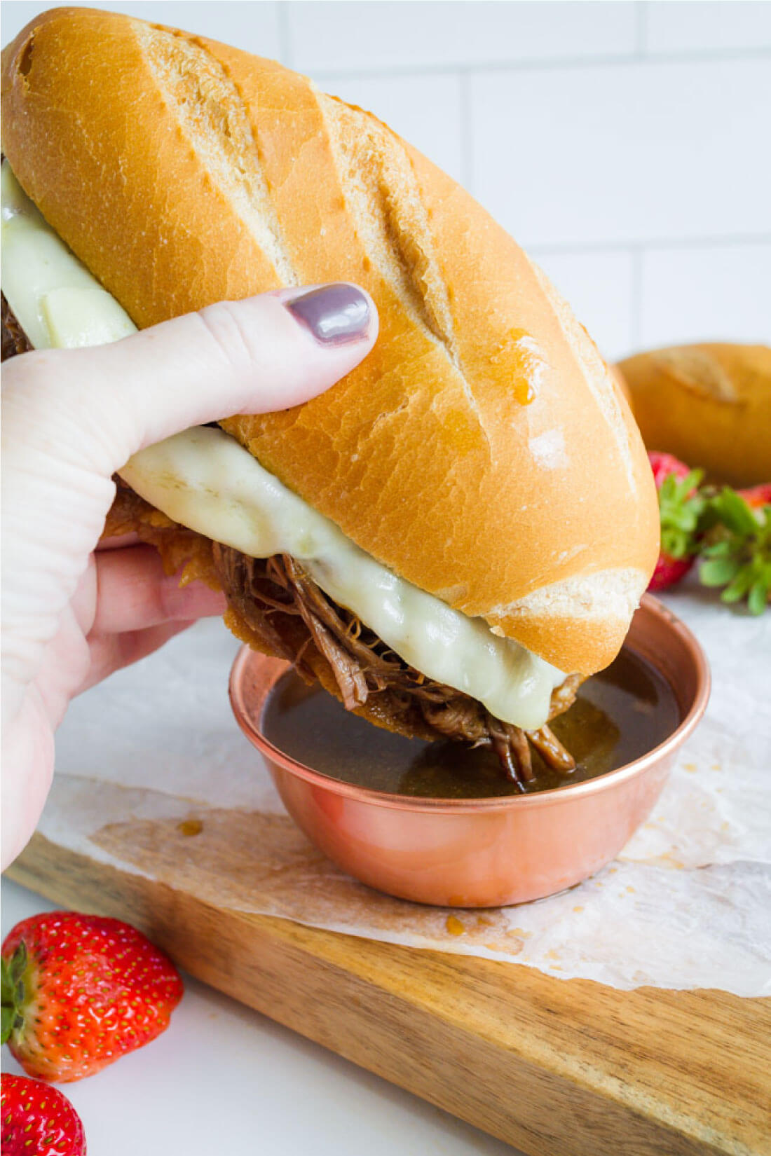 Dipping French Dip sandwiches into au jus sauce.