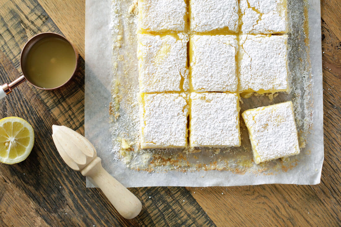 Lemon Bars up close cut into squares with lemon